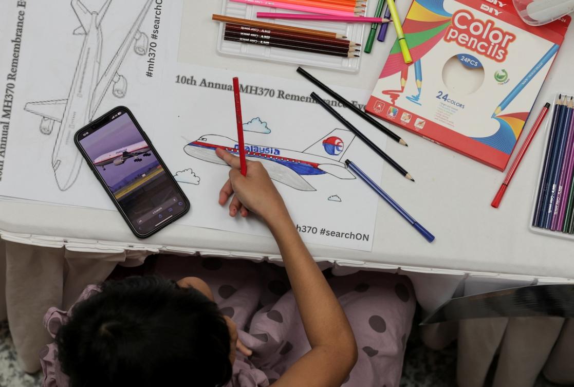 Above, a child colors a drawing of an airplane during a remembrance event marking the 10th anniversary of the disappearance of Malaysia Airlines flight MH370, in Subang Jaya, Malaysia March 3, 2024. (Reuters file photo)