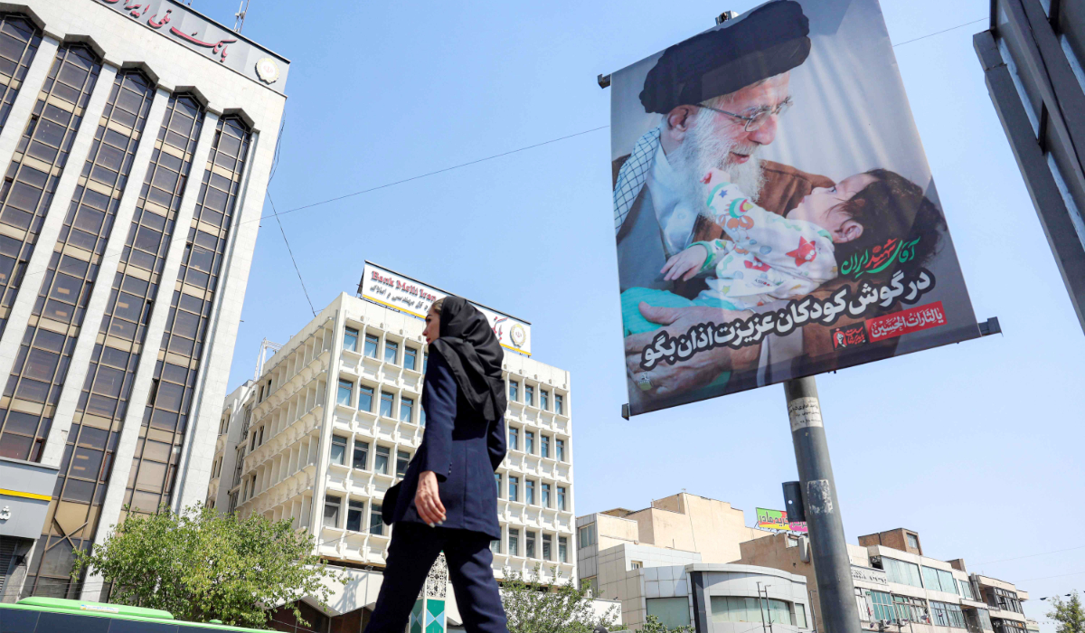 A woman crosses a road past a mourning billboard depicting Iran's slain supreme leader Ali Khamenei in Tehran on June 30, 2026 ahead of his public funeral. (AFP)