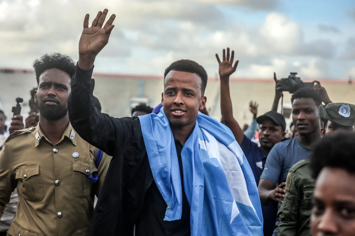 Somali international referee Omar Abdulkadir Artan waves to supporters while draped in the Somali flag as he is welcomed ahead of a solidarity football match after returning to Somalia in Mogadishu on June 10, 2026. (AFP)