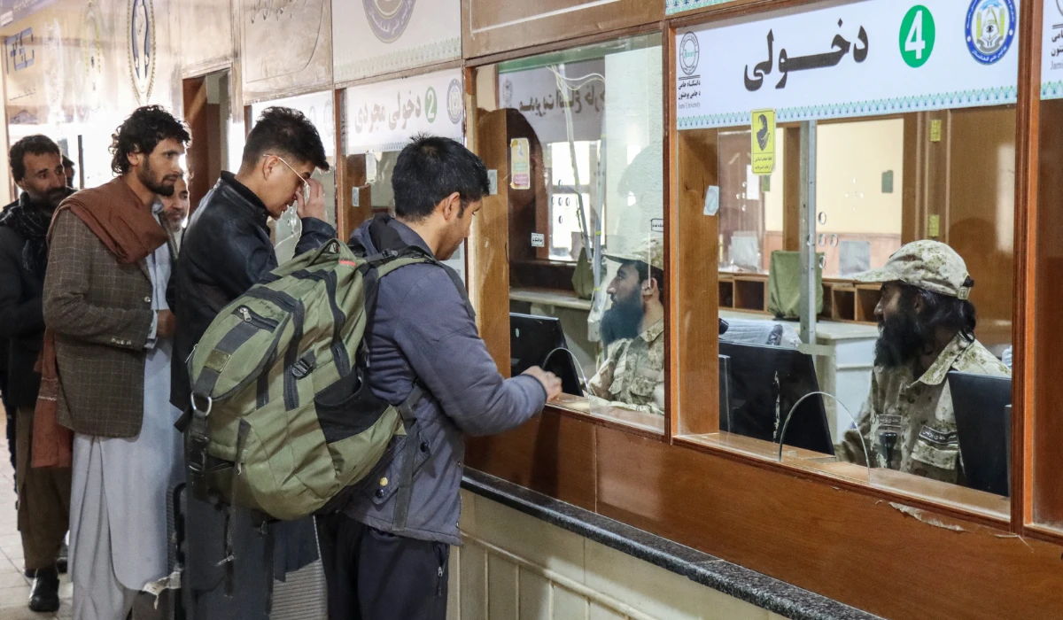 Taliban security personnel check passports of Afghan nationals upon their arrival from Iran at the Islam Qala border crossing between Afghanistan and Iran in Herat province on March 5, 2026. (AFP)