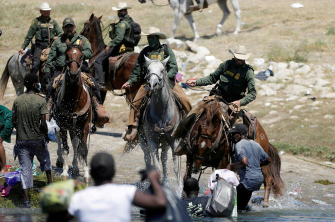 US border patrol officers cut the way of migrants asylum seekers as they are trying to return to the US along the Rio Grande river, after having crossed back into Mexico to buy food in 2021. (Reuters/File)