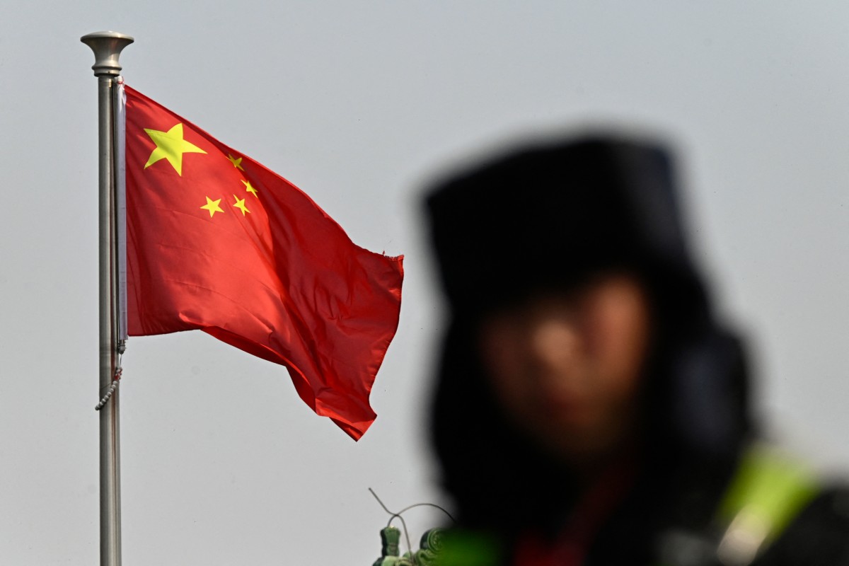 A security guard is seen next to a waving Chinese flag at a tourist area of Beijing, March 8, 2026. (Files/AFP)