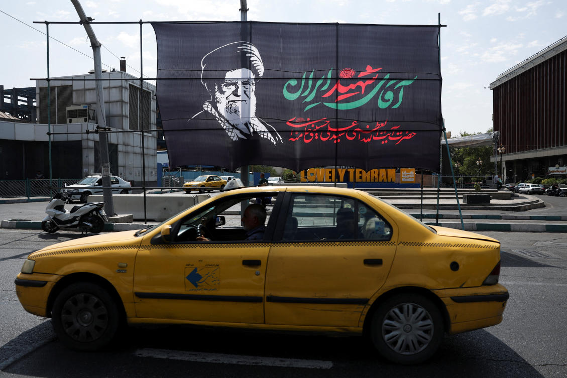 People drive past a banner with a picture of Iran's late Supreme Leader Ayatollah Ali Khamenei in Tehran on Wednesday. (Via Reuters)