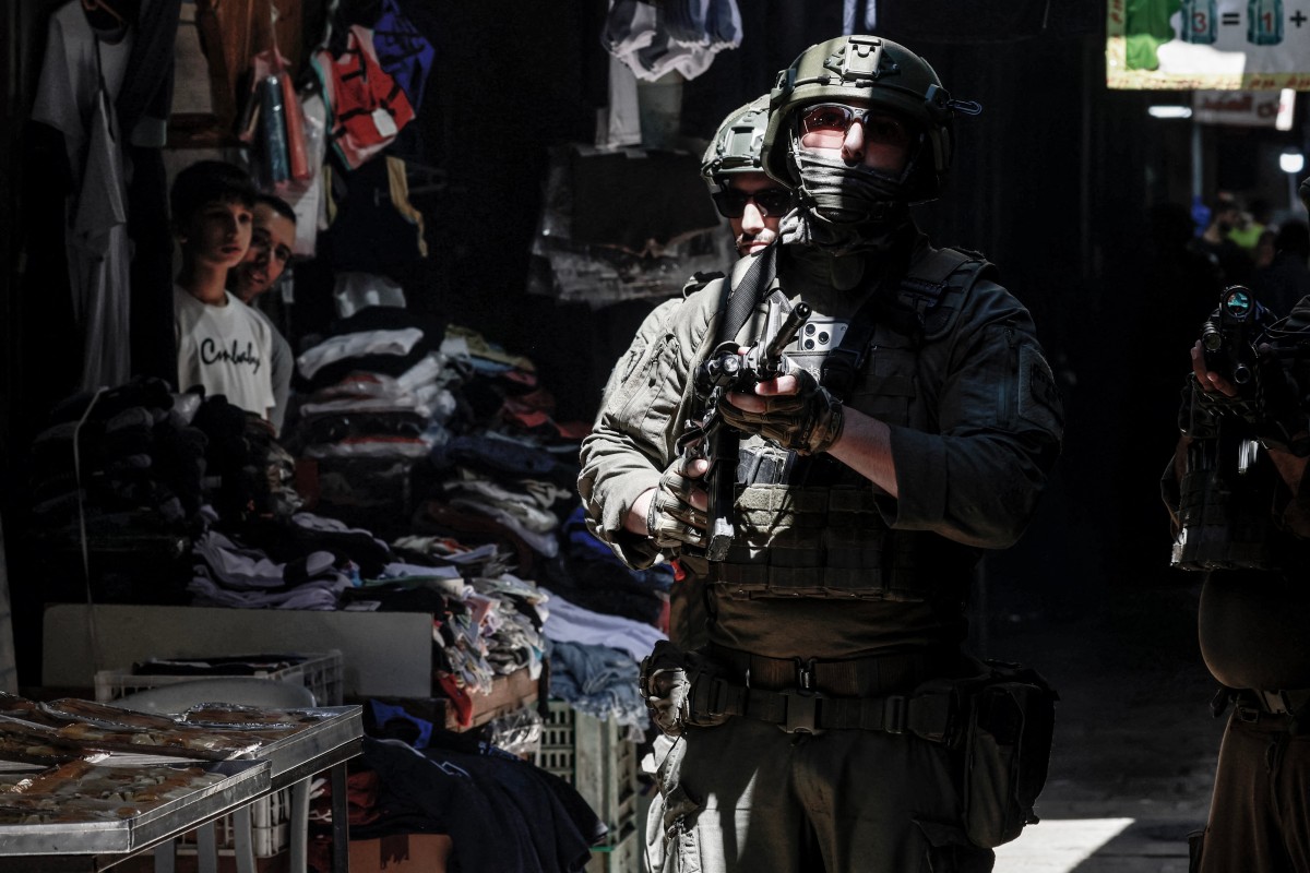 Palestinians look at Israeli soldiers patrolling the market in the Old City of Nablus in the northern Israeli-occupied West Bank. (AFP)