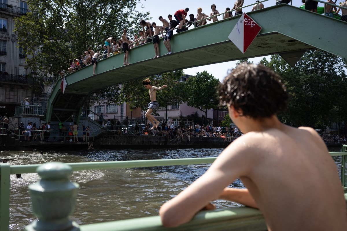 Youths jump into the Canal Saint-Martin during a heatwave in Paris, France. (AFP)