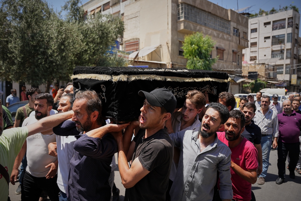 Mourners carry the coffin of Fathi Muhammad Saeed Qabbani, who was killed Tuesday when an explosive device detonated in a cafe near Damascus' main courthouse complex. (AP)