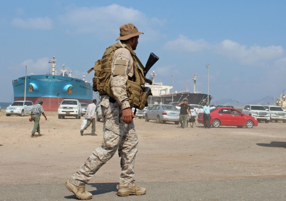 A soldier loyal to Saudi-led coalition forces stands guard near ships docked in the southern Yemeni port of Aden. (AFP/File)
