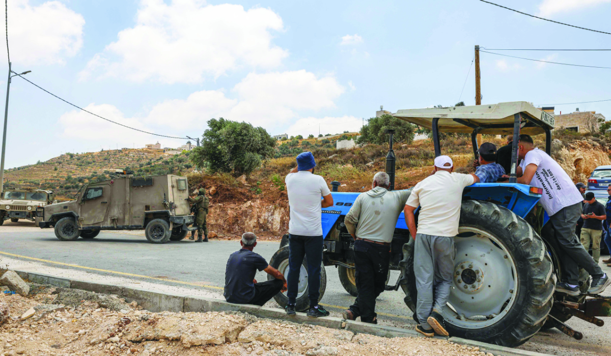 Palestinians wait after Israeli soldiers prevented them on Saturday from returning to their homes and lands in the village of Qabalan, south of Nablus. (AFP)