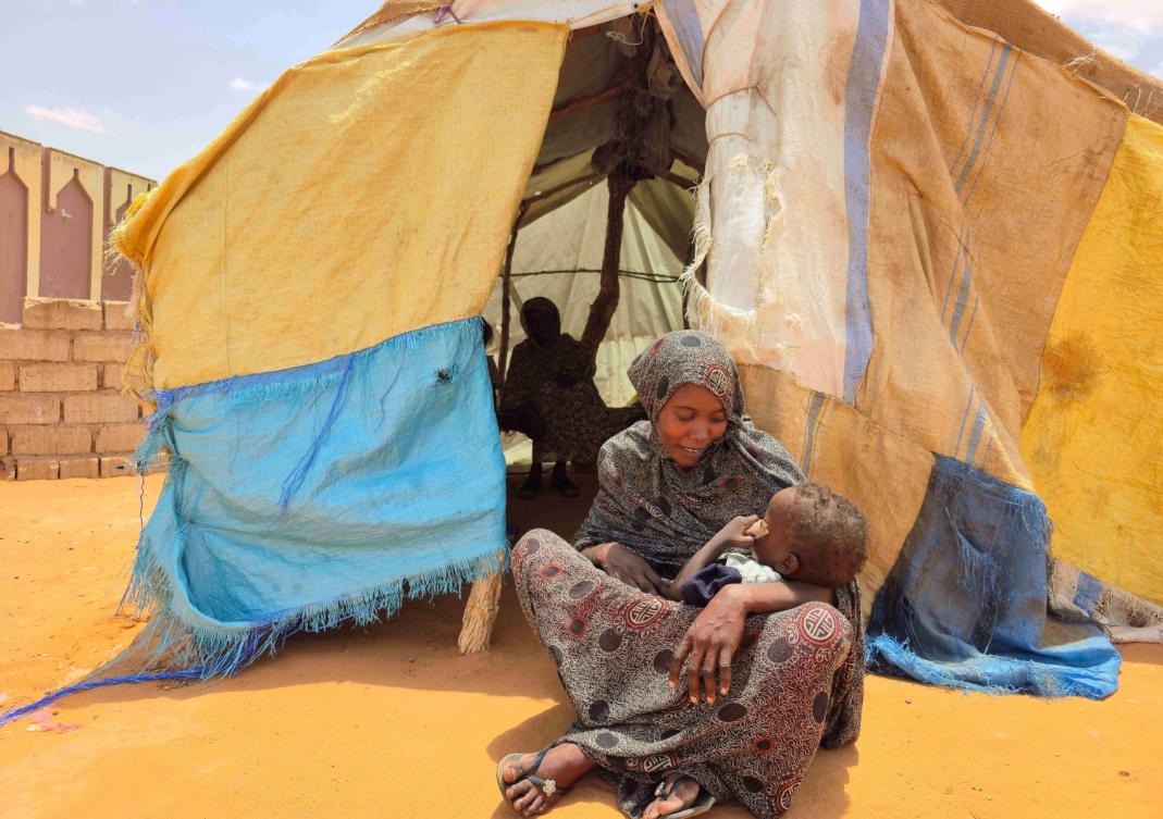 Sudanese woman sits with her child in Al-Rahmaniyah camp for displaced people, near the city of El-Obeid in the southern Kordofan region. (File/AFP)