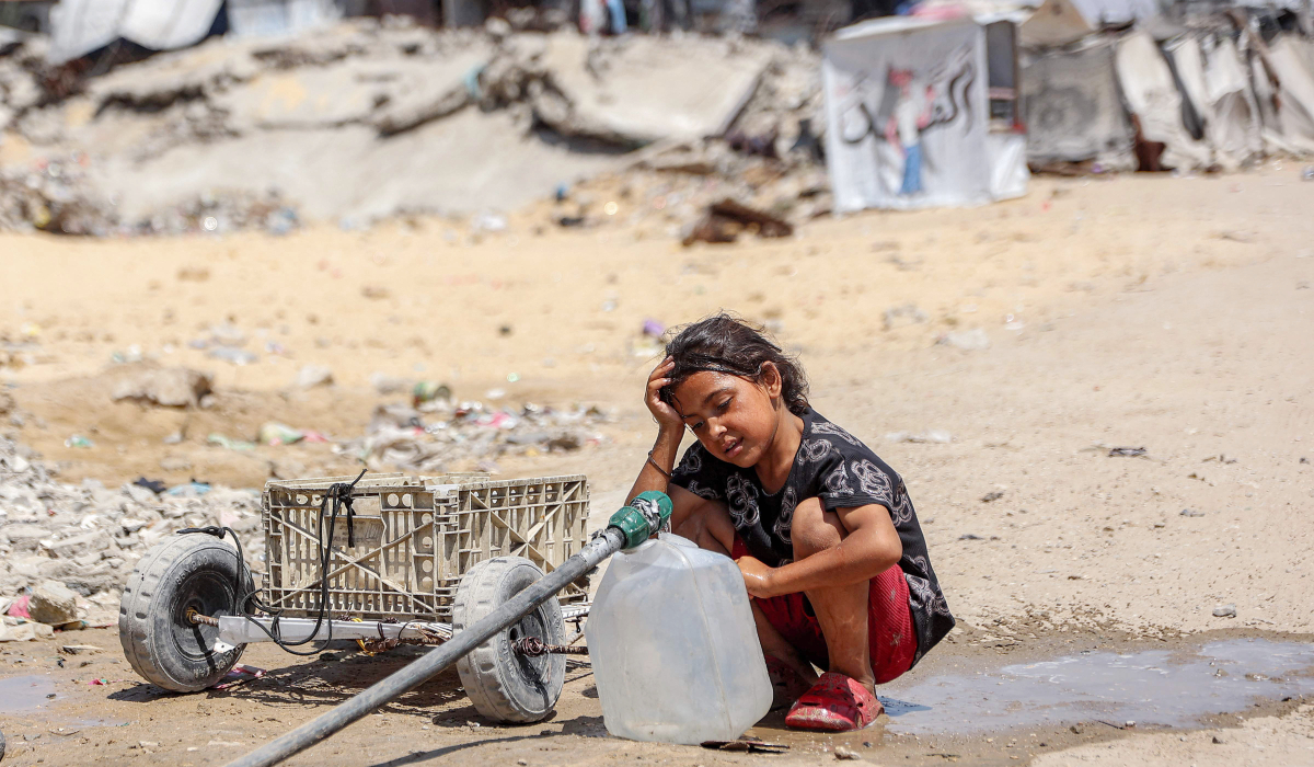 A girl fills containers with water drawn from the leftovers of underground pipes at a camp for people displaced by war in the Sheikh Radwan neighbourhood of Gaza City on July 6, 2026. (AFP)