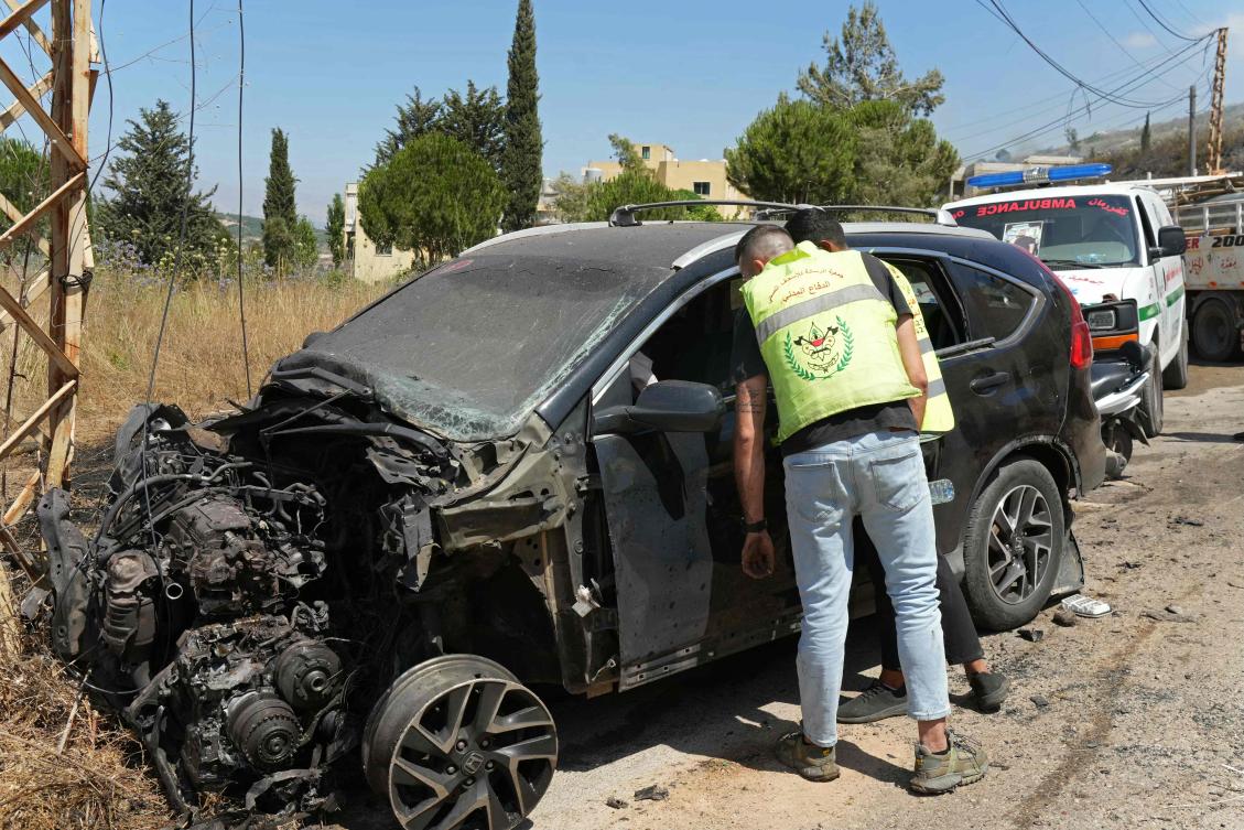 First responders inspect a vehicle damaged by an Israeli strike in the southern Lebanese village of Kfar Roummane on Friday. (AFP)