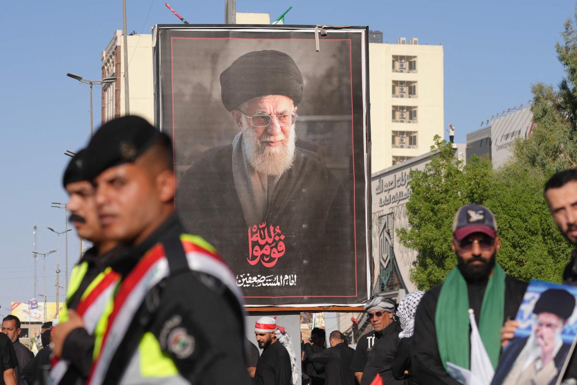 Security forces stand guard in front of a portrait of Iran's slain supreme leader Ali Khamenei as mourners gather for a funeral procession in Najaf on Wednesay. (AFP)