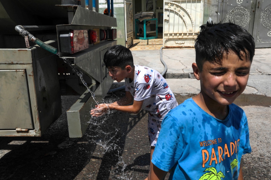 Boys splash in portable water being distributed by a mobile tanker, as summer temperatures soar in Iraq. (AFP)