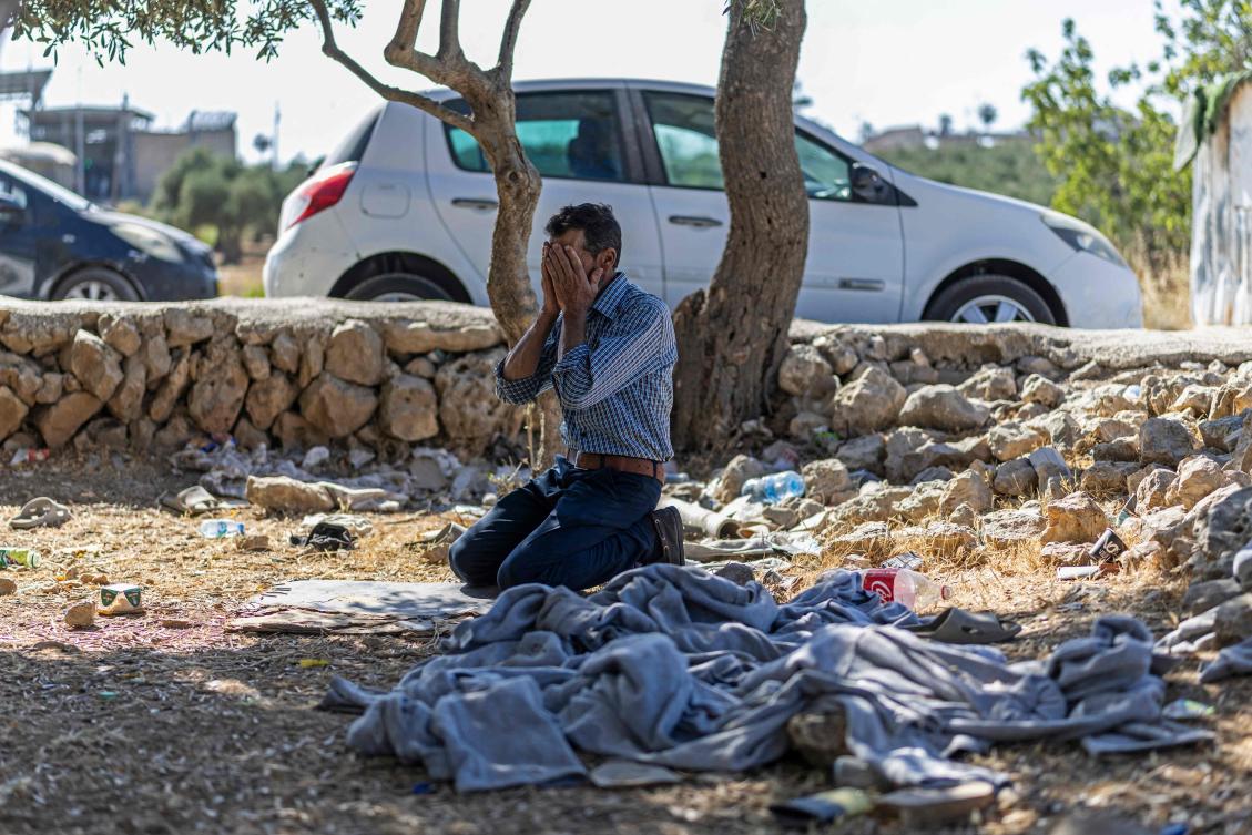 A Palestinian man offers prayers beside a pile of prisoner's clothes while waiting for his relative to be released from Israeli prison at the checkpoint on the outskirts of Israeli occupied West Bank city of Ramallah on July 8, 2026. (Photo by ilia YEFIMOVICH / AFP)