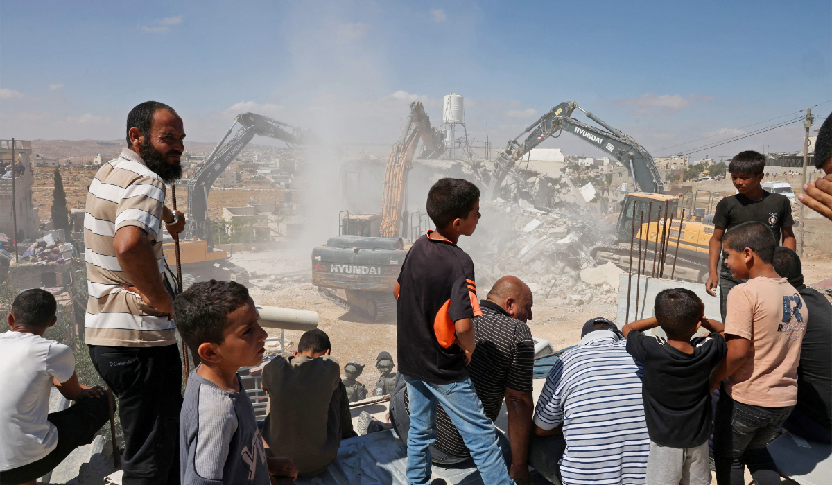 People watch Israeli excavators demolish a Palestinian home reportedly built without a permit in the village of Al-Rifayia, south of Hebron in the occupied West Bank, on July 9, 2026. (AFP)