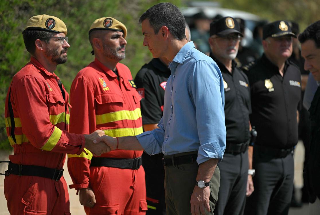 Spain's Prime Minister Pedro Sanchez (R) shakes hands with emergency services personnel as he arrives in the area of a wildfire that killed at least 13 people, at the command post set in Turre, Almeria Province, on July 13, 2026. The toll from the deadly wildfires in southern Spain rose to 13 on July 12, 2026 after a British woman died of her injuries in hospital, officials in Andalusia region announced. (Photo by JORGE GUERRERO / AFP)