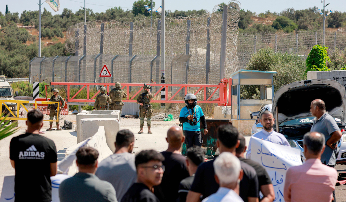 People from the Palestinian town of Azzun, east of Qalqilya in the occupied West Bank, gather by the vehicle barrier at the entrance of the town on July 12, 2026, to protest the years-long closure of the barrier by Israeli forces. (AFP)