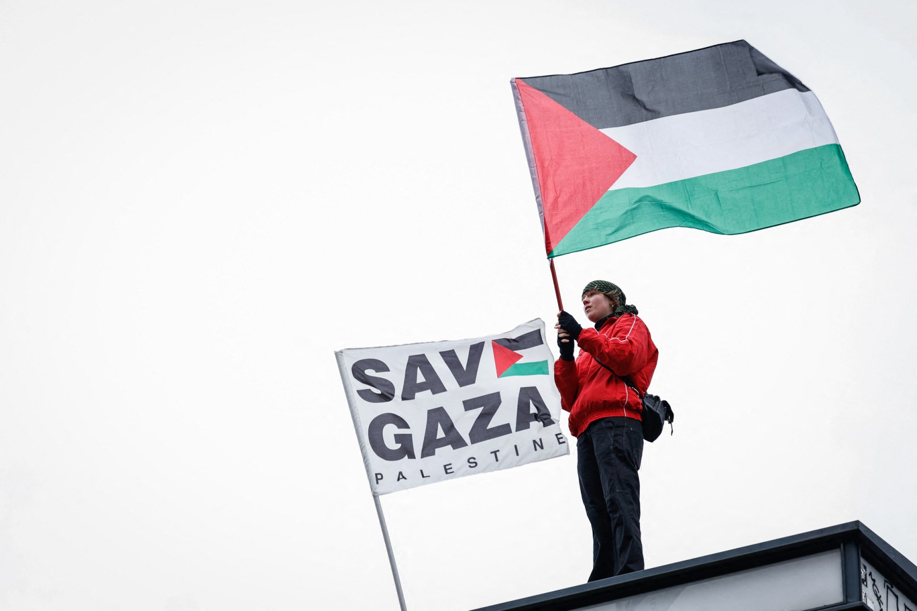 A protester waves a Palestinian flag next to a flag reading ‘Save Gaza’ during a demonstration called by a dozen pro-Palestinian organizations in support of the Palestinian people in Brussels, Jan. 26, 2025. (AFP)