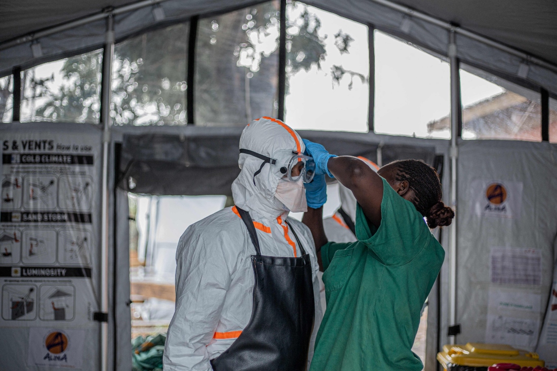 A hygiene worker helps a doctor put on personal protective equipment (PPE) before entering the Rwampara Ebola Treatment Centre (ETC) to care for patients with Ebola virus disease in Bunia, Ituri, in the east of the Democratic Republic of Congo. (AFP)