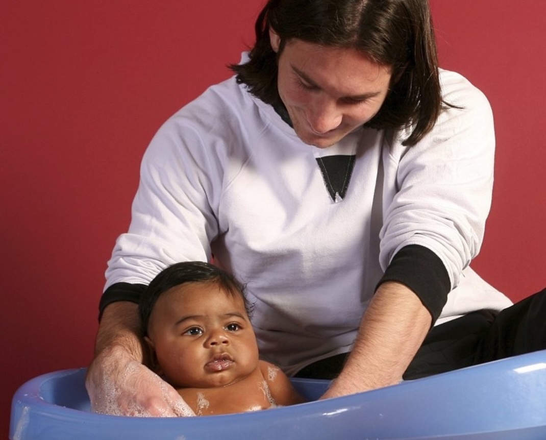The famous photo of Lionel Messi bathing a five-month-old Lamine Yamal. (Supplied)