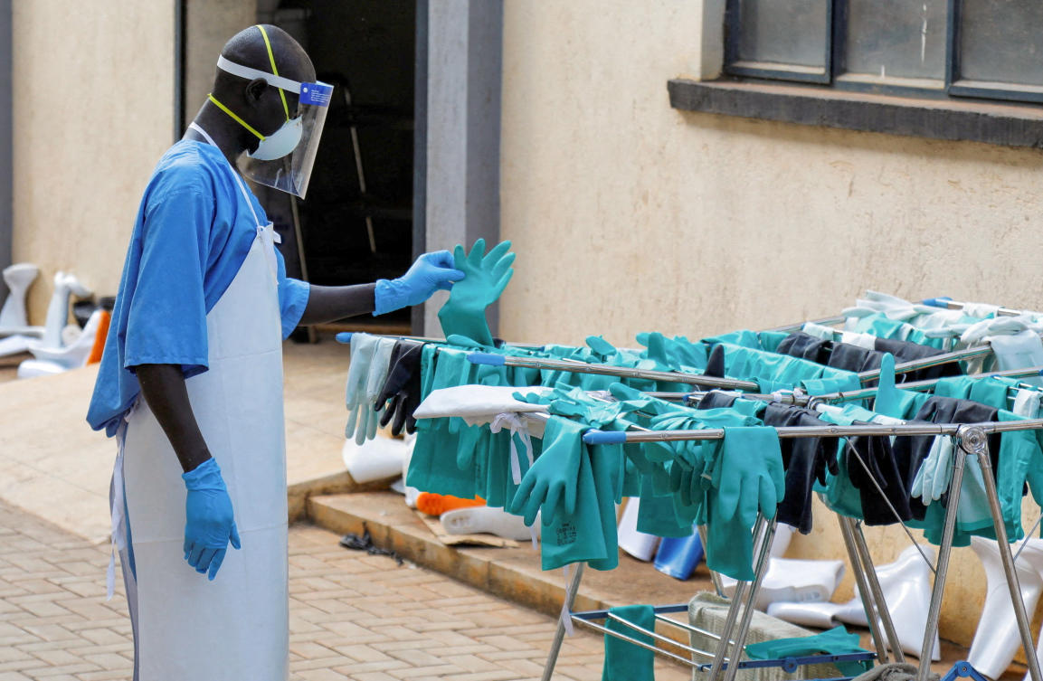 A Ugandan worker collects a rubber glove from the airing line during a visit by WHO’s Director-General Tedros Adhanom Ghebreyesus at the Mulago National Referral Hospital Isolation Unit, as aid agencies intensify efforts to contain a new Ebola outbreak involving the Bundibugyo Virus, in Kampala, Jun. 8, 2026. (Reuters/File)