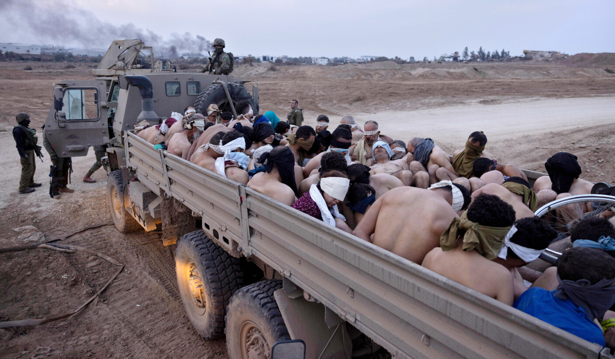 Israeli soldiers stand by a truck packed with bound and blindfolded Palestinian detainees, in Gaza, Dec. 8, 2023. (AP file photo)