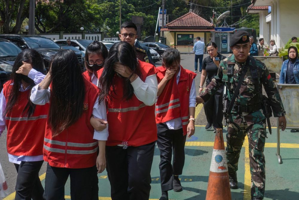 An Indonesian military officer escorts defendants to a trial in a baby trafficking case at the Bandung District Court in Bandung, West Java, on July 21, 2026. (AFP)