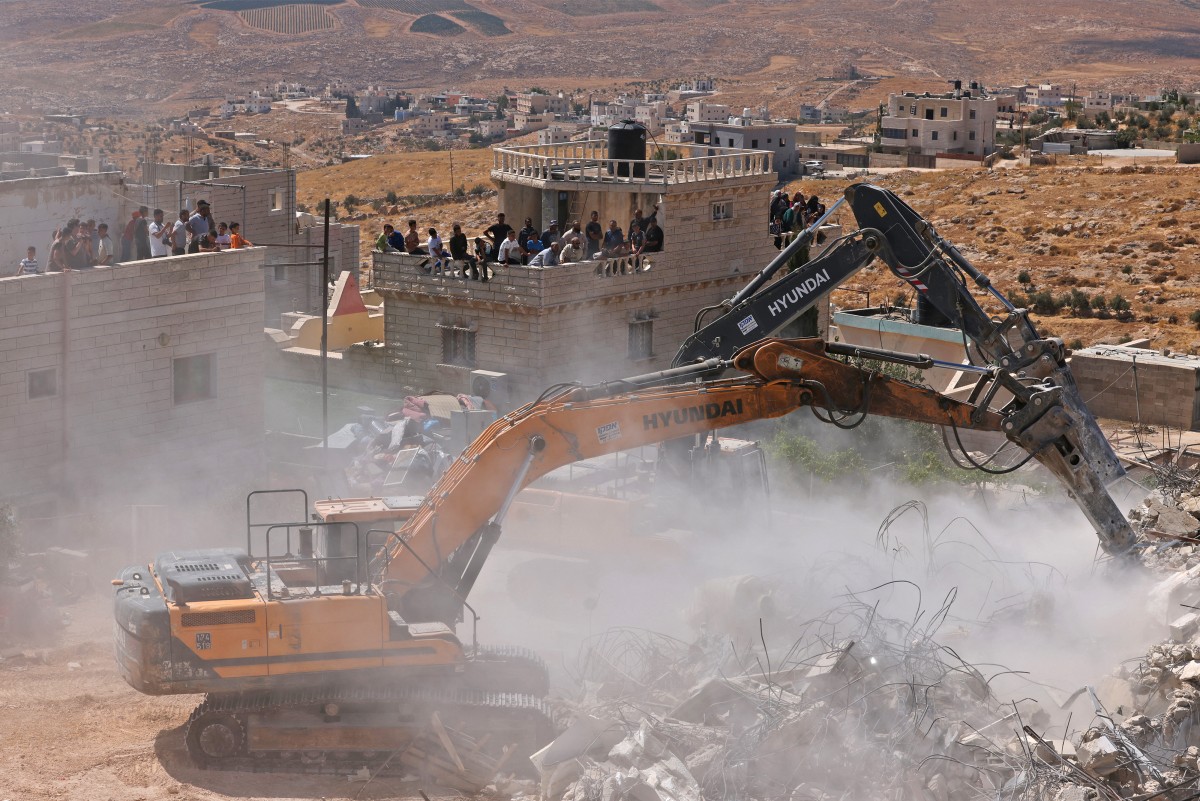 People watch Israeli excavators demolish a Palestinian home reportedly built without a permit in the village of al-Rifayia, south of Hebron in the occupied West Bank, July 9, 2026. (AFP)