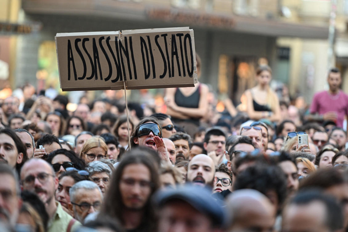 A protester holds a placard reading in Italian “State murderers” above a crowd during a protest following the death of Abderrahim Fakir in Bologna, Jul. 20, 2026. (Reuters)