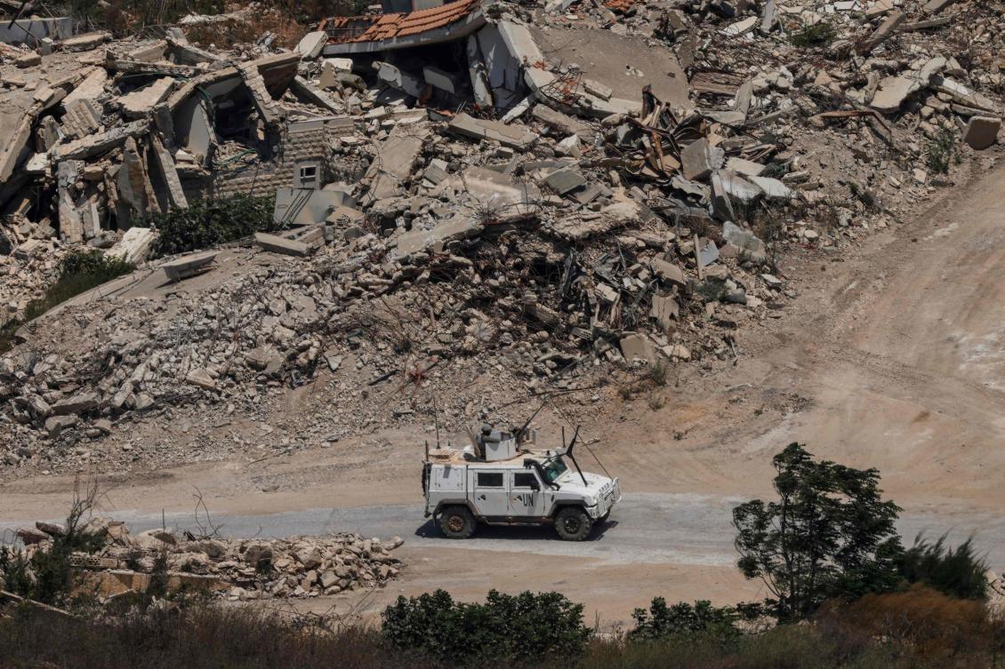 This picture, taken from a position in northern Israel, near the border with Lebanon, shows a UNIFIL armoured vehicle driving past destroyed buildings in southern Lebanon on July 22, 2026. (AFP)