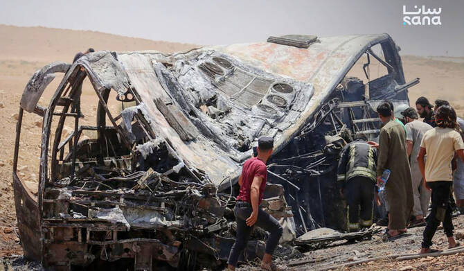 People and first responders inspect the damage at the scene of the collision of two passenger buses on the Damascus-Deir Ezzor road between the Sukhna and Palmyra areas. (SANA)