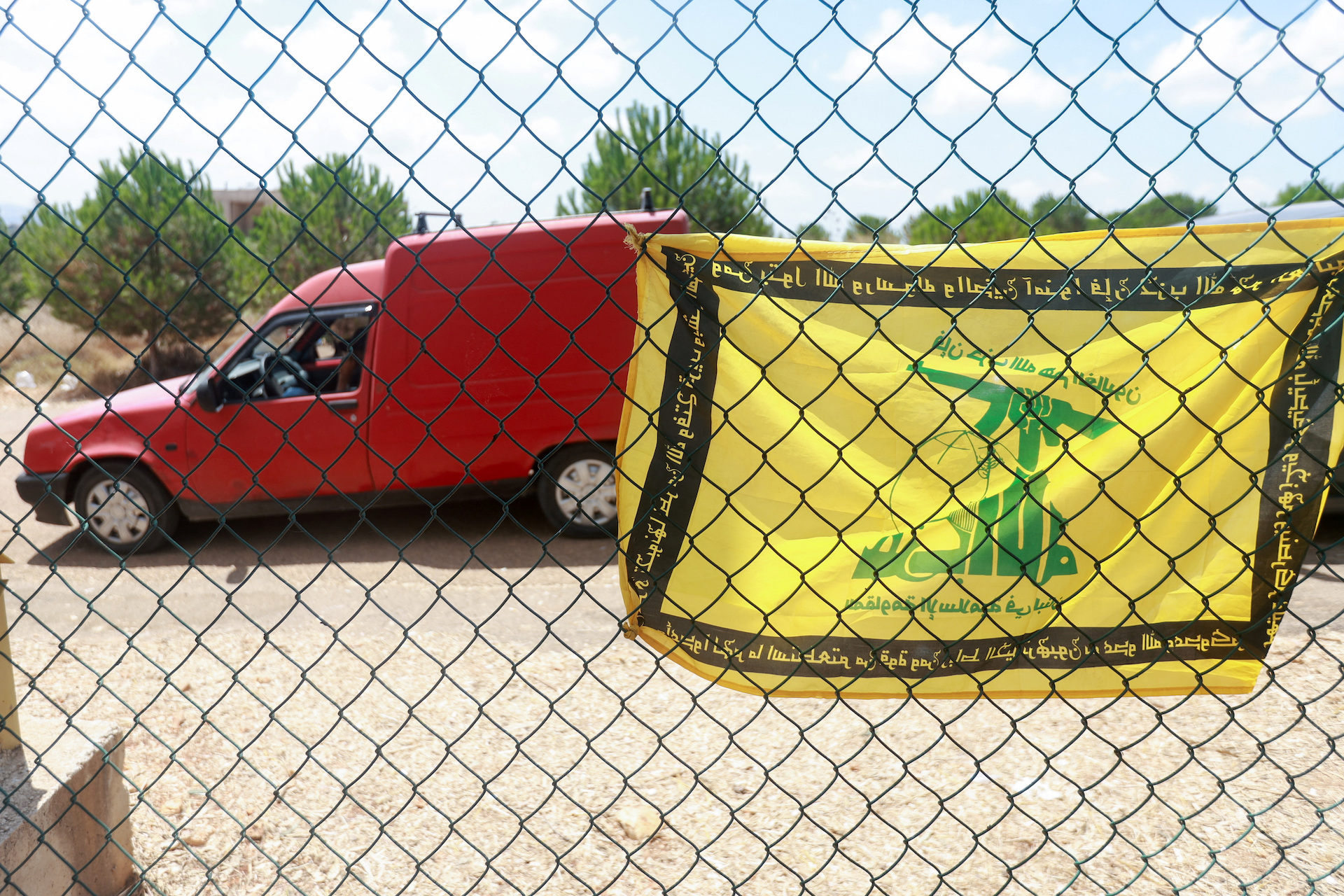 A flag with the pattern of the Hezbollah flag hangs on a fence as residents wait to enter the town of Zawtar al-Gharbiyeh, following the withdrawal of Israel forces under a U.S.-brokered plan, in southern Lebanon, July 25, 2026. (Reuters)