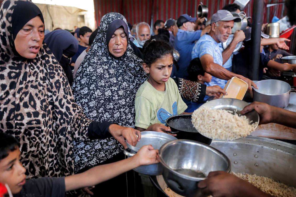 People queue to receive meals from a charity kitchen at the Maghazi camp for Palestinian refugees in the central Gaza Strip on July 26, 2026. (AFP)