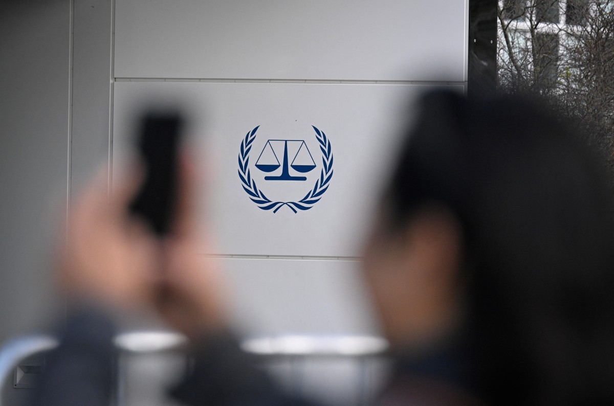 A bystander takes an image of the logo outside the exterior of the International Criminal Court (ICC) in The Hague on March 28, 2026. (Photo by JOHN THYS / AFP)