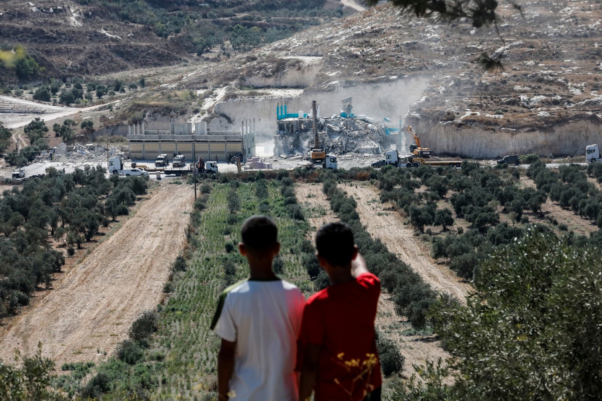 Palestinian children watch as Israeli forces oversee the demolition of a building containing shops and flats, citing the lack of a building permit, in Anzah, south of the Palestinian city of Jenin, in the northern Israeli-occupied West Bank, Jul. 27, 2026. (Photo by Mohammad MANSOUR / AFP)