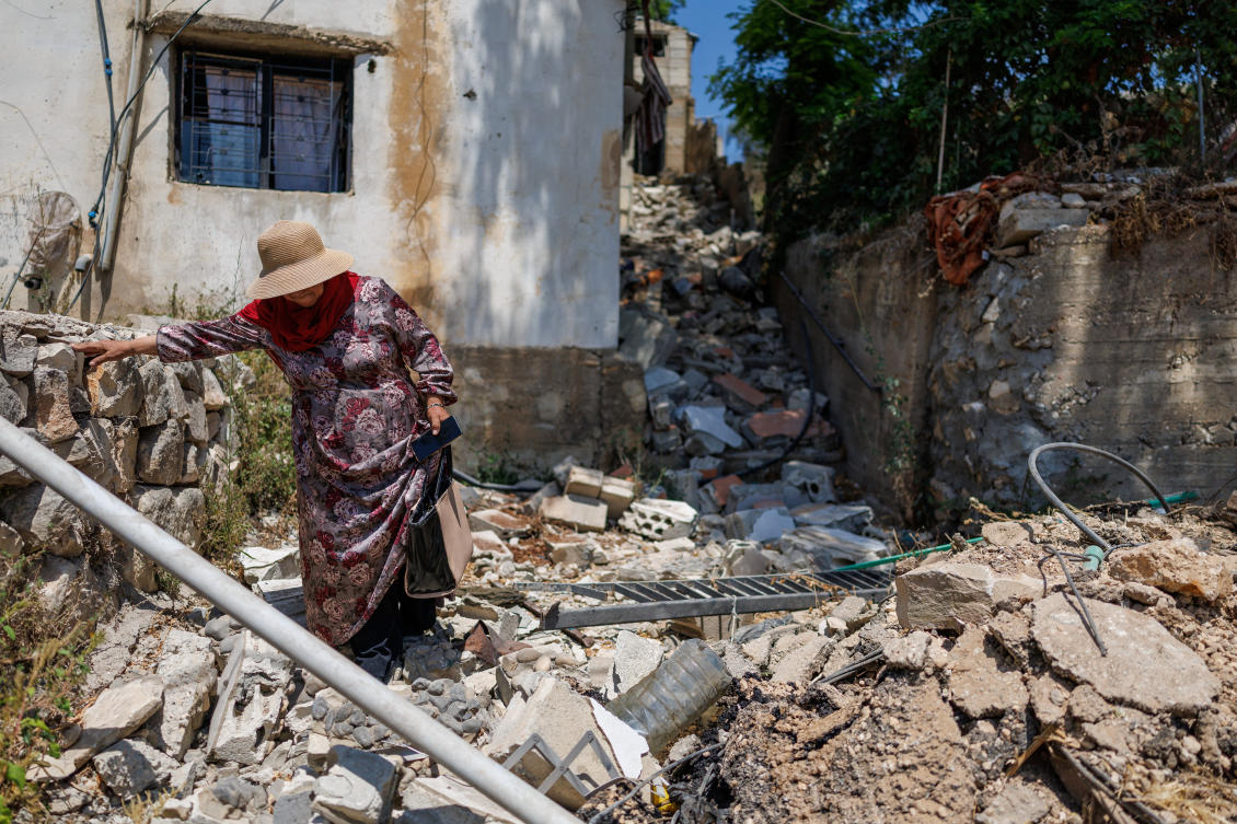 Haifa Shkair, a resident, walks outside her damaged house after returning to Zawtar al-Gharbiyeh in southern Lebanon following the deployment of Lebanese soldiers in one of three so-called pilot zones. (Reuters)