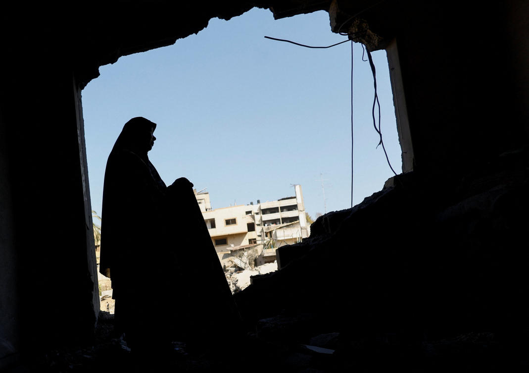 A Palestinian woman inspects her damaged home after an Israeli strike on a nearby mosque in Gaza City on Wednesday. Hamas said it had agreed to a deal on Friday to disarm. (Reuters)