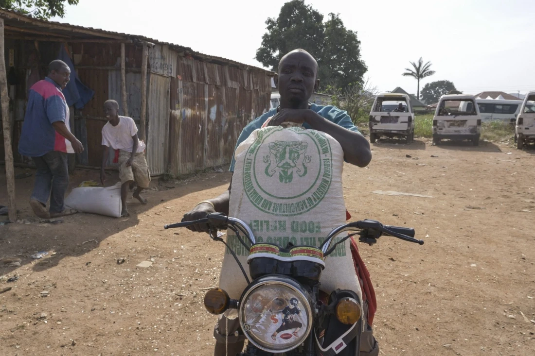 A man sits on his motorcycle while holding a bag of food in Jos, Nigeria. (AFP)