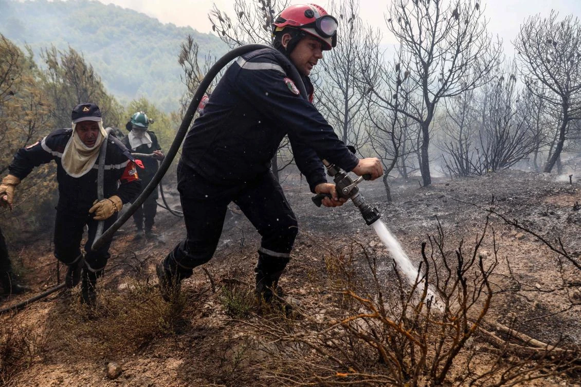 Firefighters from a civil protection unit battle a wildfire in a mountainous area near the town of Al Hachimia, Bouira Province, on Jul. 21, 2026. (AFP)