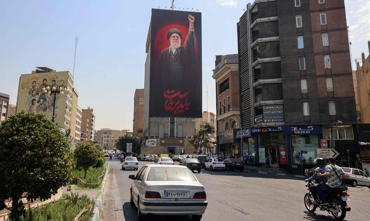 Iranians drive their vehicles past a huge banner of Iran's slain Ayatollah Ali Khamenei in Tehran on July 19, 2026. (AFP)
