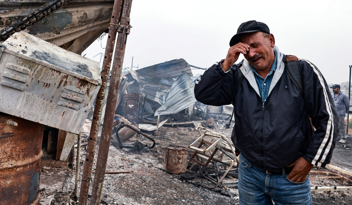 Palestinian farmer Ahmad Khalil reacts as he stands amid the charred remains of his agricultural installation, following an attack by Israeli settlers in the village of Sinjil, north of the occupied West Bank city of Ramallah. (AFP file photo)