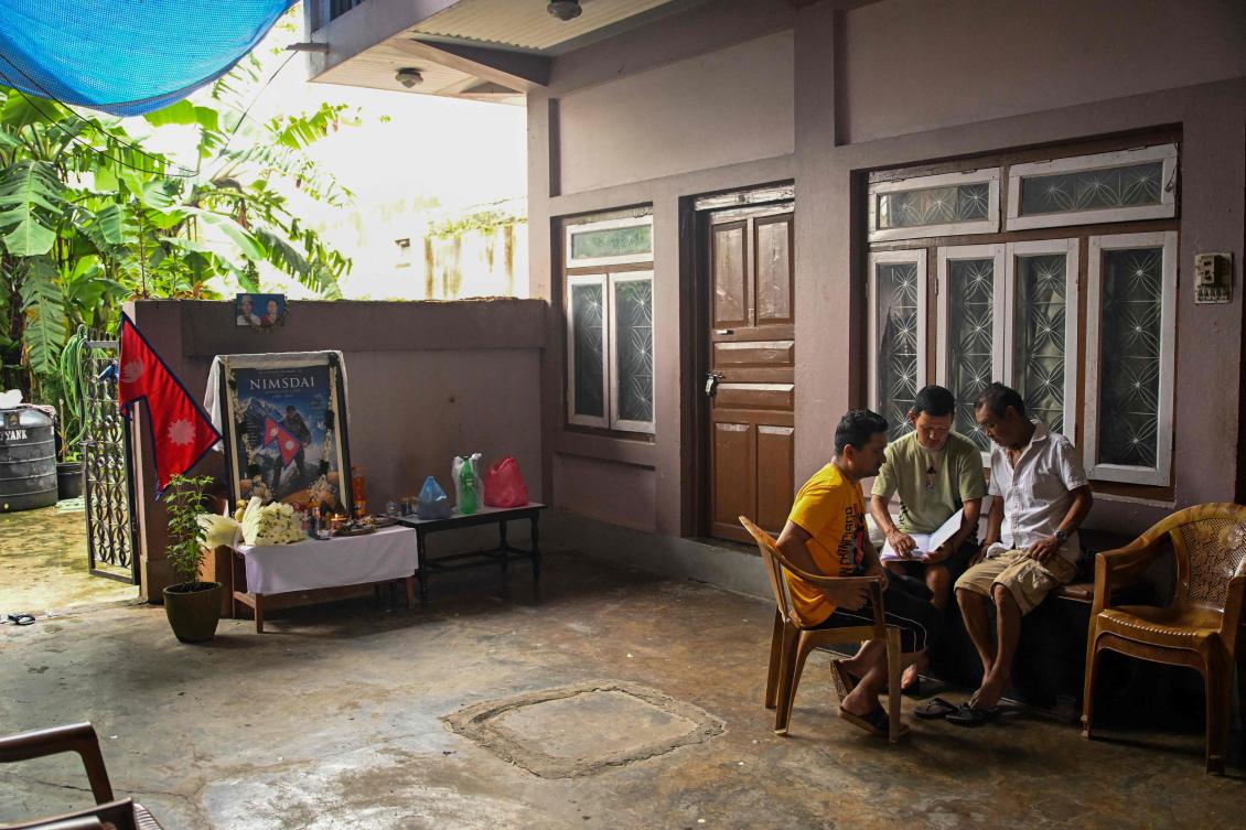 Above, relatives sit near a portrait of mountaineer Nirmal Purja at his home in Chitwan on Aug. 3, 2026, after his demise in an avalanche on Pakistan’s Broad Peak. Search teams recovered the bodies Purja and three other missing climbers on Wednesday. (AFP)