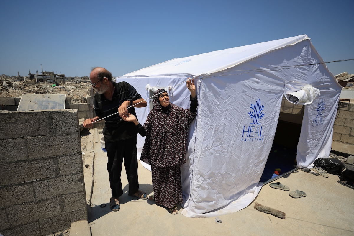 A Palestinian couple fixes their tent, set up on the rooftop of a house after being displaced due to the further advancement of the Israeli military, in Gaza City on Aug. 1, 2026. (Reuters)