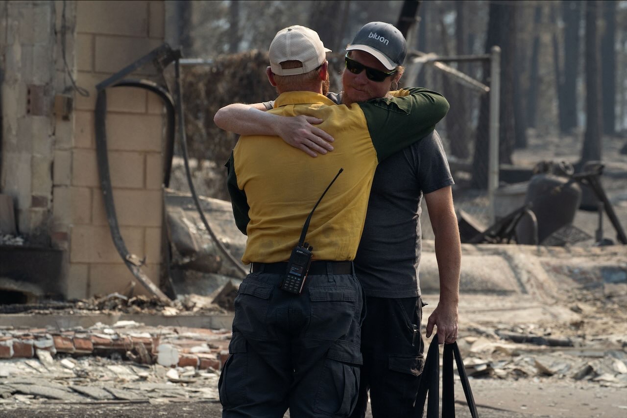 A wildfire victim whose home burned during the Old Trails fire hugs a firefighter medic after surveying his lost home in Spokane, Washington, US, August 4, 2026. (Reuters)