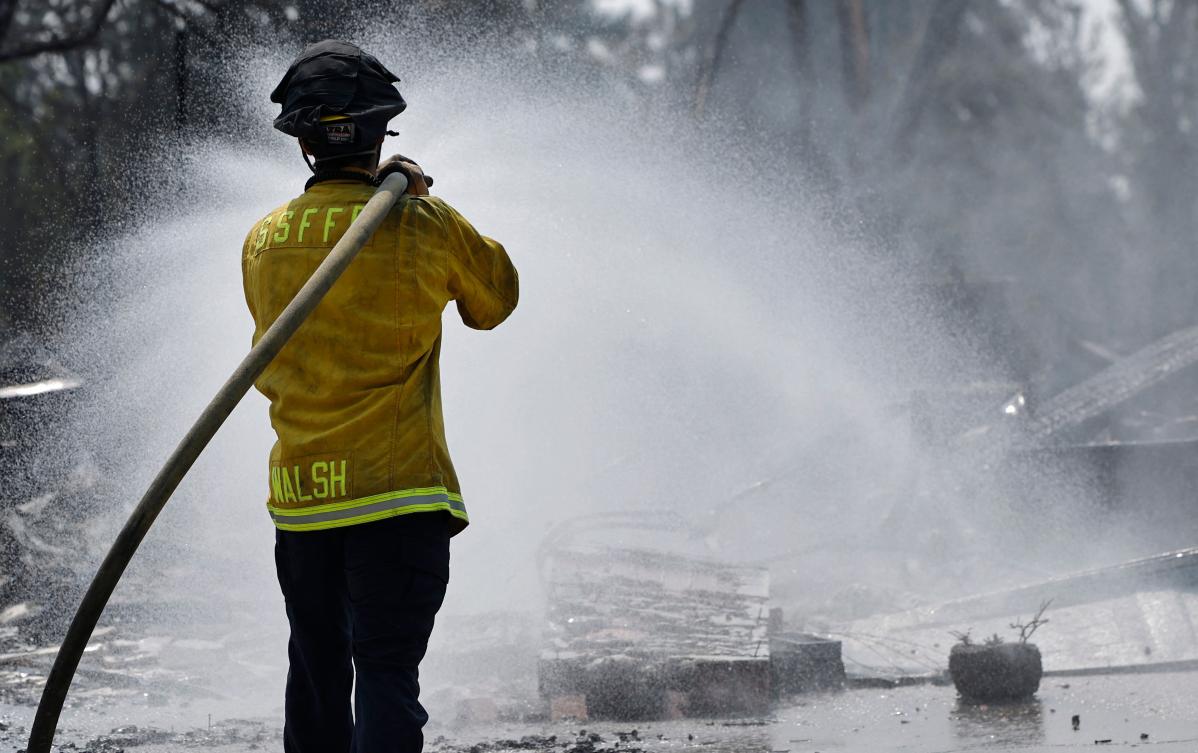 SPOKANE, WASHINGTON - AUGUST 06: A South San Francisco Fire Department firefighter hoses down the remains of a home destroyed in the Old Trails Fire on August 6, 2026 in Spokane, Washington. Firefighters are attempting to extinguish hotspots ahead of projected stronger winds in the region. Fueled by strong winds amid drought, fast-moving wildfires burned over 10,000 acres combined in the Spokane area over the weekend, destroying more than 700 structures, including many homes. 65,000 people were forced to evacuate, and one man was arrested on suspicion of first-degree arson in the Old Trails Fire. Mario Tama/Getty Images/AFP (Photo by MARIO TAMA / GETTY IMAGES NORTH AMERICA / Getty Images via AFP)