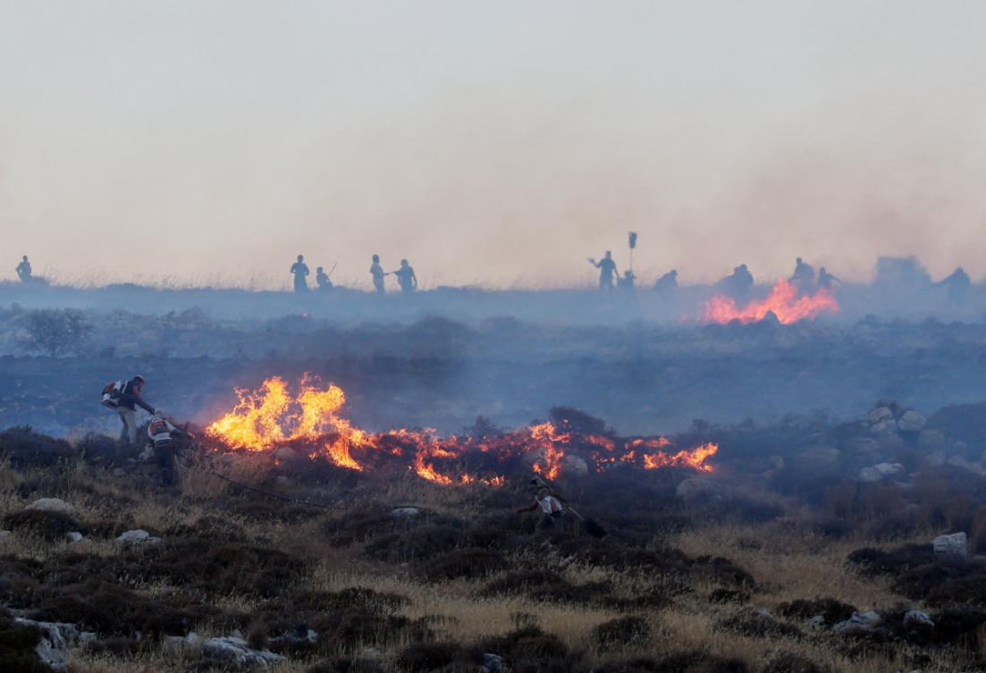 Israeli settlers put out a fire by a settler outpost, near the Palestinian town Taybeh in the Israeli-occupied West Bank, July 17, 2026. (Reuters/Ammar Awad/File Photo)