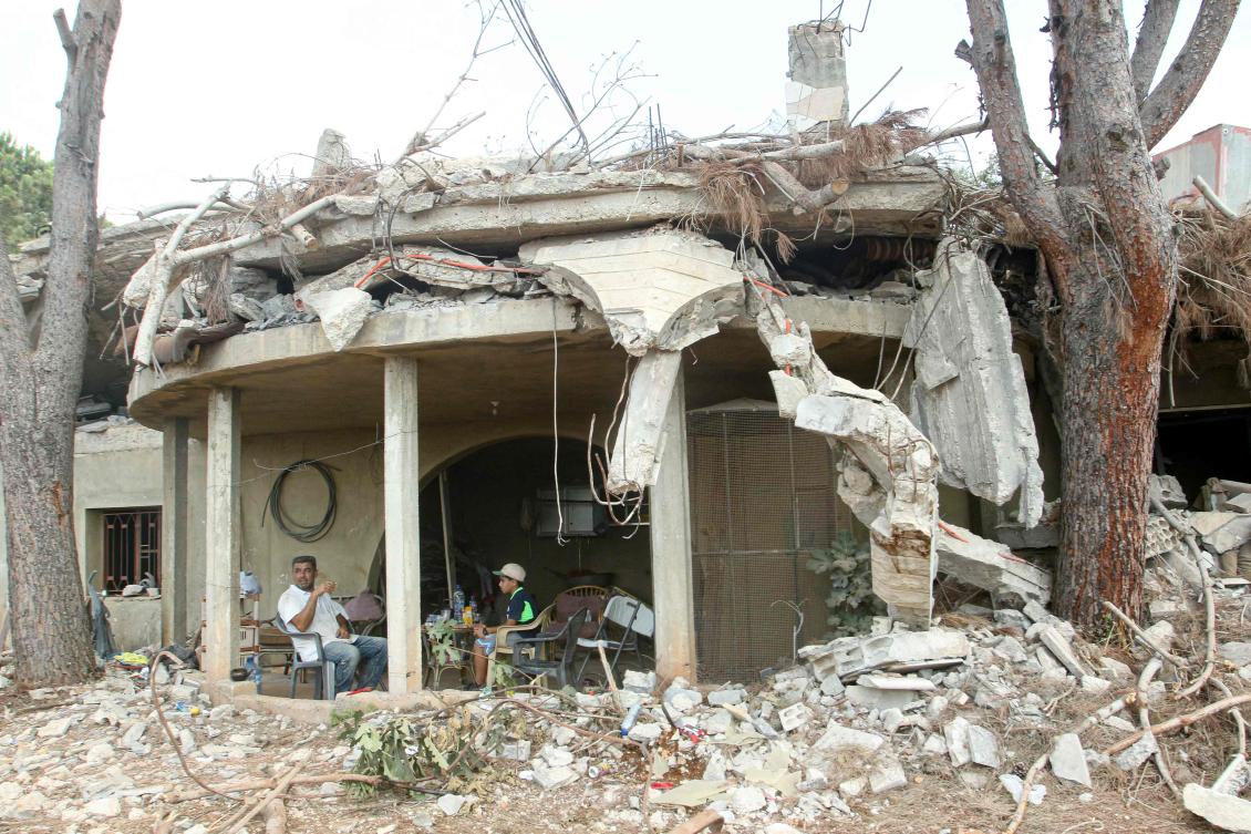 Above, residents sit at the entrance of their home destroyed by the Israeli military in the southern Lebanese village of Zawtar Al-Gharbiyah on Aug. 8, 2026. (AFP)