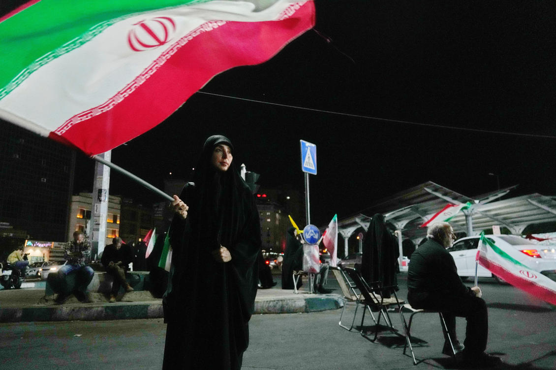A woman waves an Iranian flag during a pro-government gathering at a square in Tehran, Iran, Tuesday, Aug. 11, 2026. (AP Photo/Vahid Salemi)