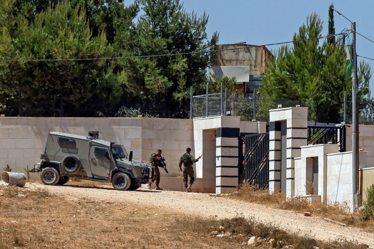 Israeli soldiers stand guard outside a Palestinian house in the village of Qusra, south of Nablus, in the occupied West Bank, on August 13, 2026. (AFP)