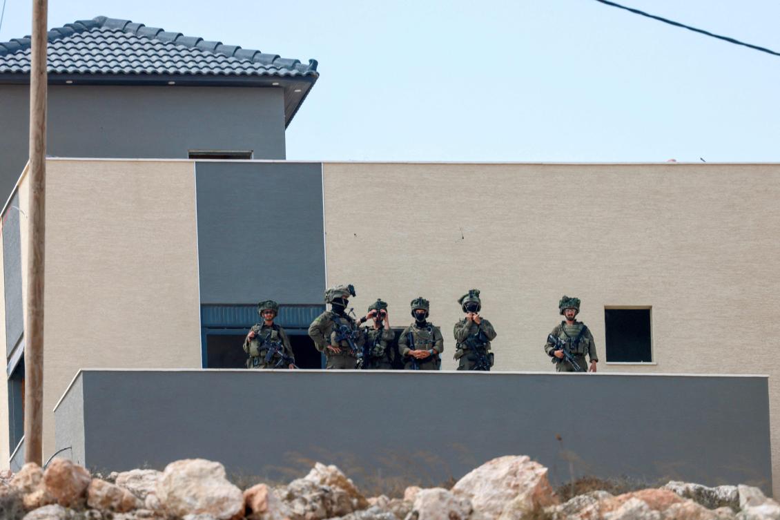 Israeli soldiers take position in a building located adjacent to the home of a Palestinian family besieged by Israeli settlers in the village of Qusra, south of the city Nablus, in the Israeli-occupied West Bank, nearly a week after the settlers began blockading Palestinian homes defying attempts by the Israeli military to remove them. (AFP)